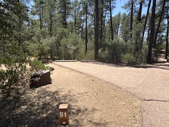 Houston Mesa, Black Bear Loop site #51 featuring entrance to the wooded site, fire pit, and picnic table.